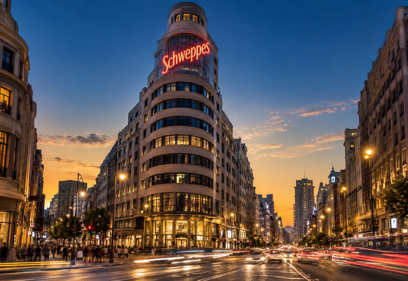 Gran Vía de Madrid al atardecer, con el edificio del letrero luminoso rojo de Schweppes